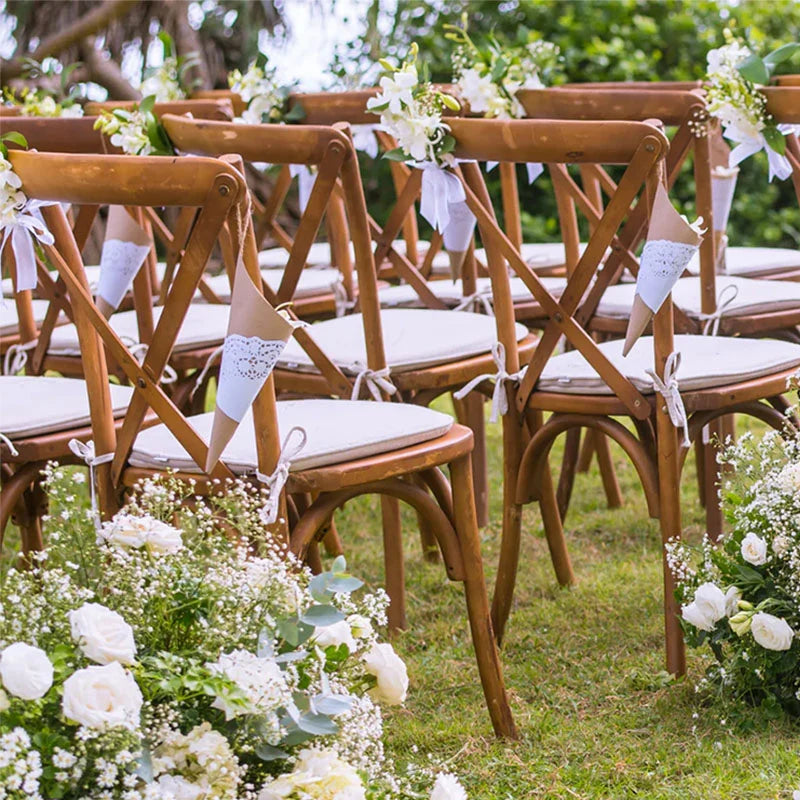 Wood crossback chairs with cushions arranged in a field for a wedding ceremony.